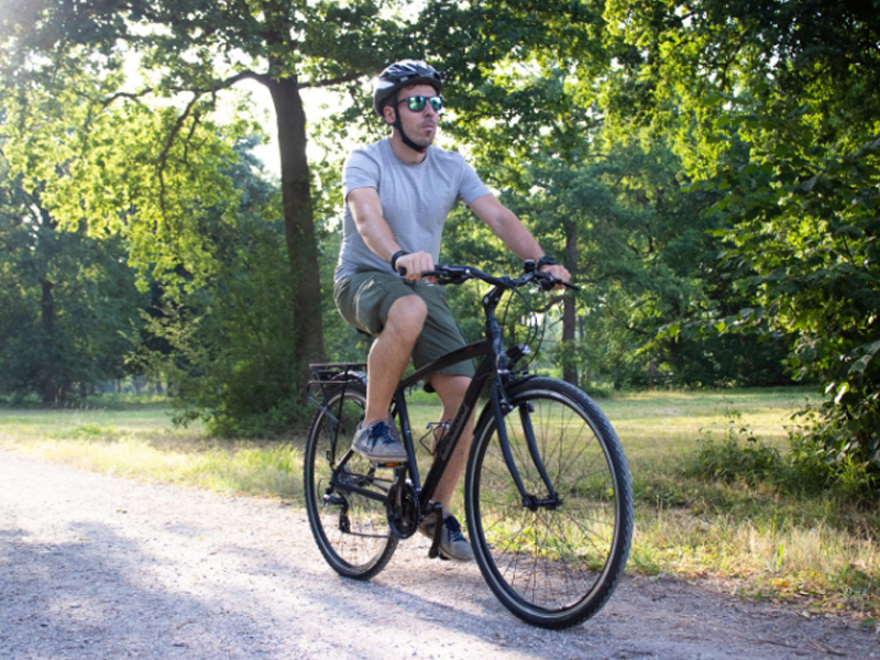 Trekking bike Day Trip di Boeris Bikes Torino guidata da un ragazzo con caschetto e occhiali su una strada sterrata in mezzo ad un bosco