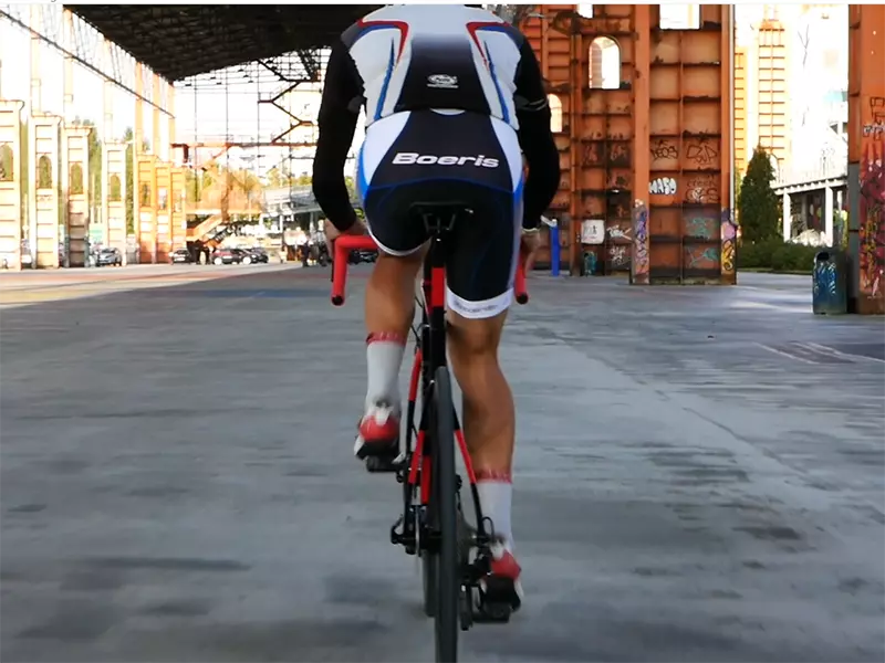 Ciclista in sella ad una Bici da strada Norden Boeris Bikes Torino Nera e Rossa fotografato di spalle 