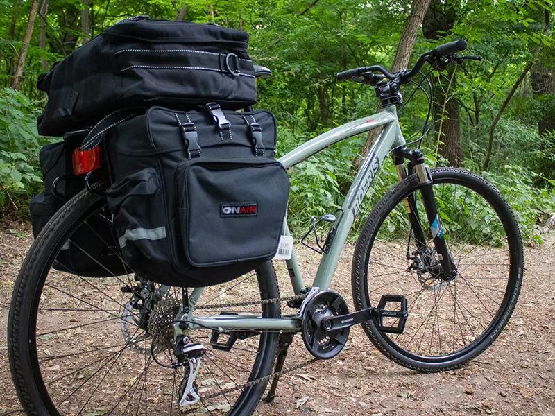 Una Trekking Bike Bikepacking Travel verde con Bikepack fotografata su una strada sterrata in un bosco