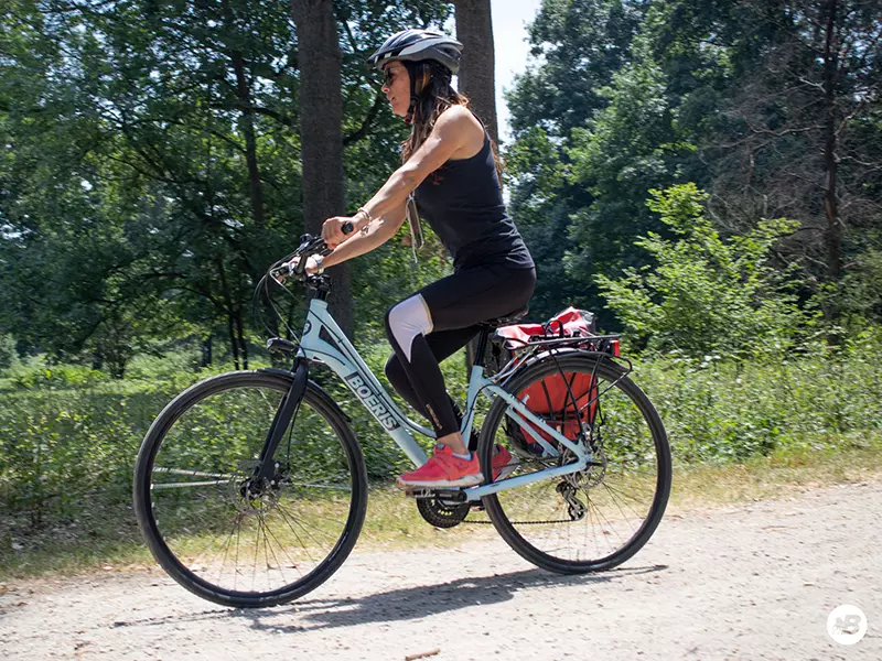 Ragazza in sella ad una bici Trekking Bikes Torino Day Trip azzurra su una strada sterrata