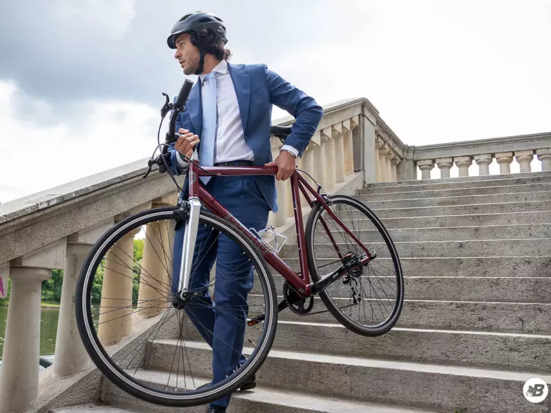 Ragazzo in completo elegante e caschetto che porta a mano giù per delle scale lungo Po la sua city bike business Boeris Bikes torino Amaranto