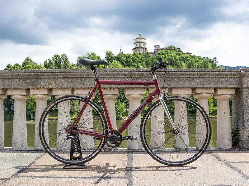 City Bike Business Boeris Bikes Torino amaranto sul lungo Po con sul sfondo la Chiesa di Santa Maria del Monte dei Cappuccini