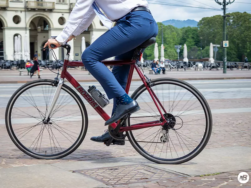 Ragazzo in completo elegante senza giacca che guida la sua city bike business Boeris Bikes Torino Amaranto in Piazza castello a Torino
