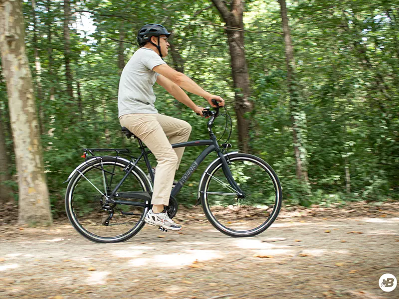 Ragazzo in sella ad una City Bike Urban travel nera Boeris Bikes Torino  su una strada sterrata in mezzo ad un bosco