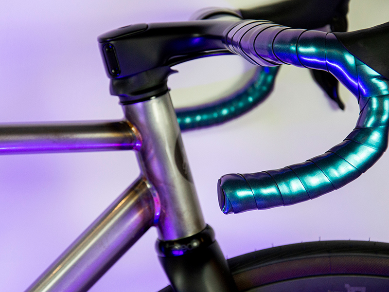 Gravel bike color panna con sella e manubrio marroni di Boeris Bikes Torino di fronte ad una siepe