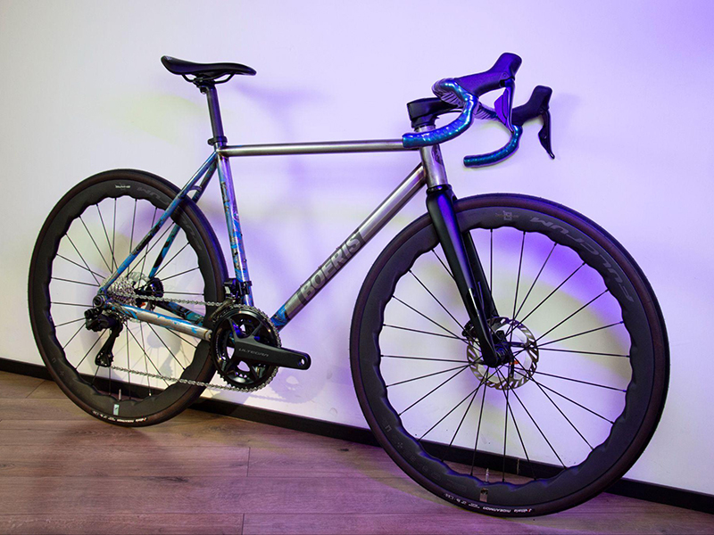 Gravel bike  color blu  con sella e manubrio neri di Boeris Bikes Torino su un cubettato vicino a fioriere