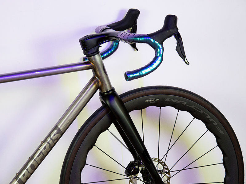 Gravel Serie X grigia in acciaio grigia di Boeris Bikes Torino fotografata al parco Dora appoggiata a un murales azzurro