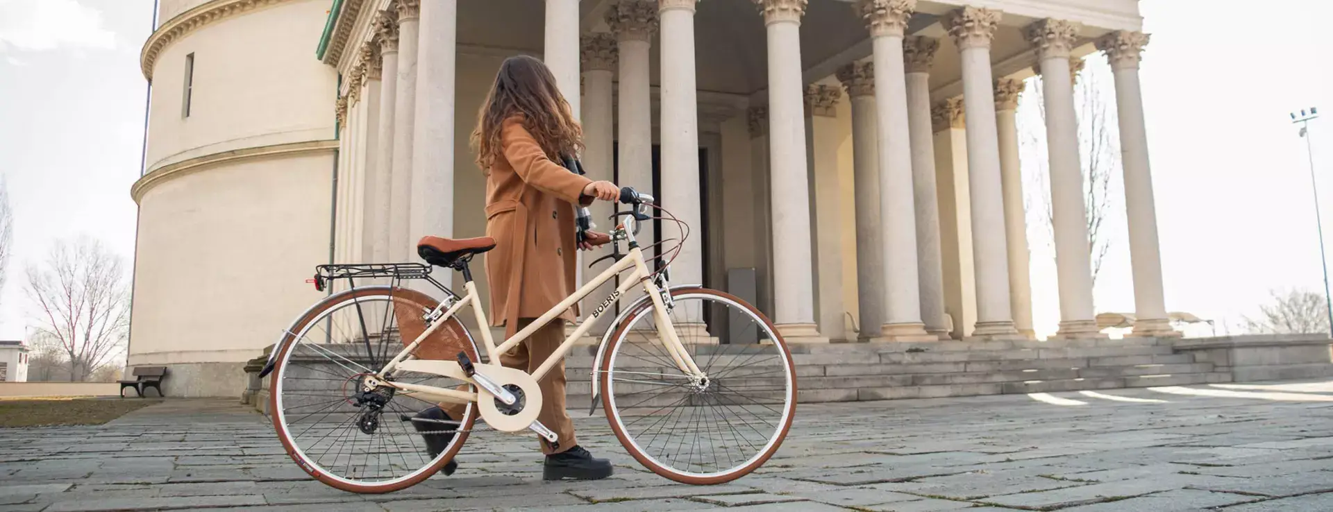 ragazza che porta a mano una City Bike Retò Boeris Bikes Torino davanti al Mausoleo della belal rosina Mirafiori
