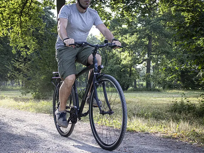 Ragazzo in sella ad una Trekking Bike Boeris Bike Torino nera in un parco cittadino