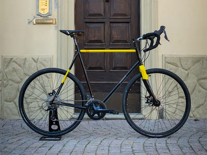 Gravel bike color nera e gialla di Boeris Bikes Torino su un cubettato davanti ad una porta