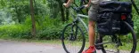 Ragazzo vestito estivo su una Trekking Bike Bikepacking Travel verde con Bikepack fotografata su una strada sterrata in un bosco