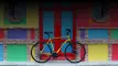 Bicicletta da strada gialla di Boeris Bikes Torino appoggiata ad una porta rossa e azzurra e un muro di mattoni colorato