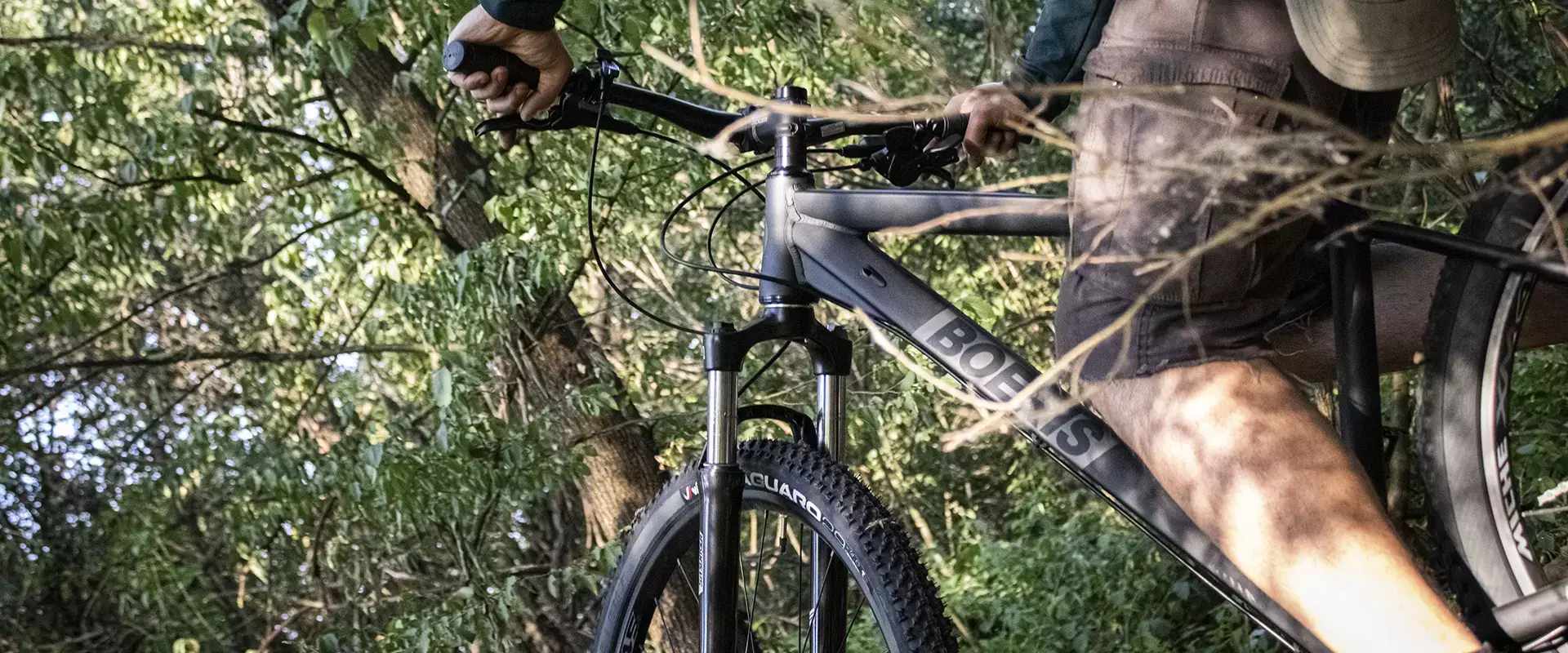 Ragazzo in sella alla sua MTB Volcano nera Boeris Bikes Torino in mezzo ad un bosco